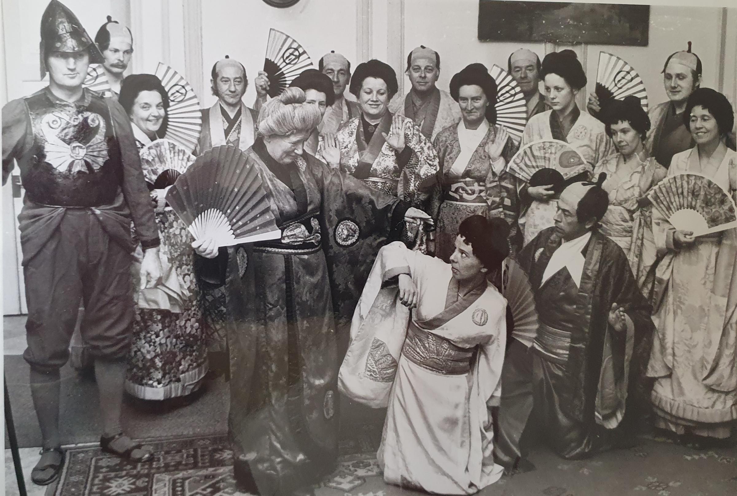 A performance of The Mikado by Great Witley Operatic Society in 1976. Enid Rea who appeared as one of the three little maids on stage in a 1950s adaptation (by Worcester Operatic and Dramatic Society), can be seen on the far right of the photograph